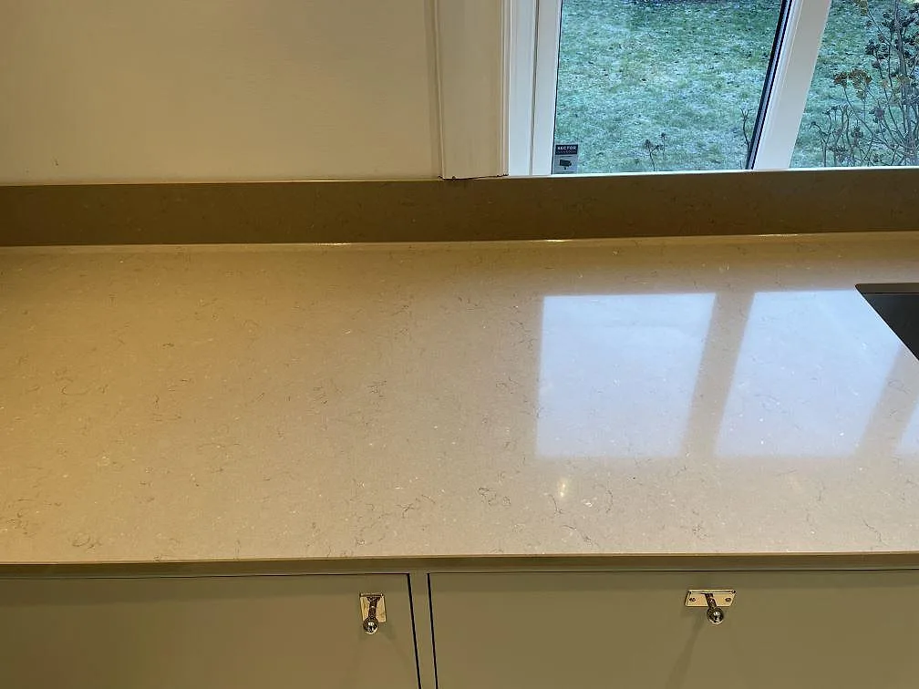 Polerad köksbänkskiva i Silestone Coral Clay med mjuk ådring och salviagröna luckor i ett kök i Malmö.