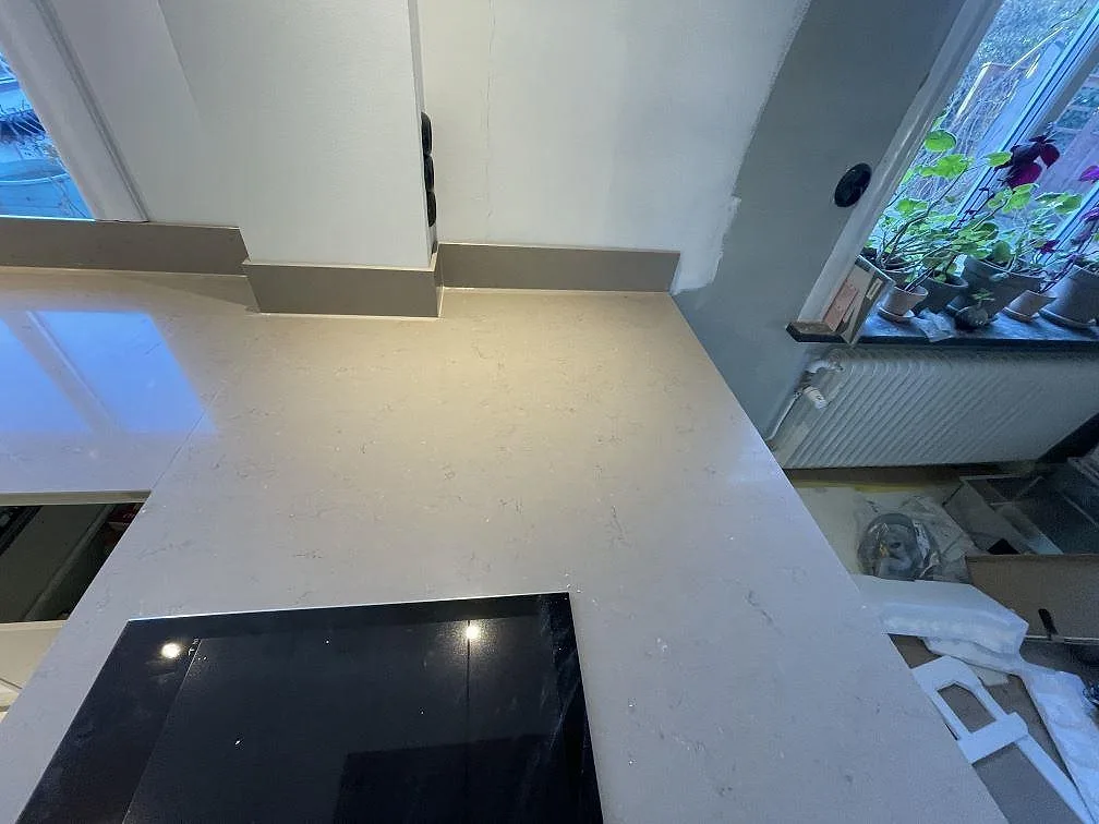 Köksbänkskiva i Silestone Coral Clay med infälld induktionshäll och fönsterbänk i samma sten i ett kök i Malmö.