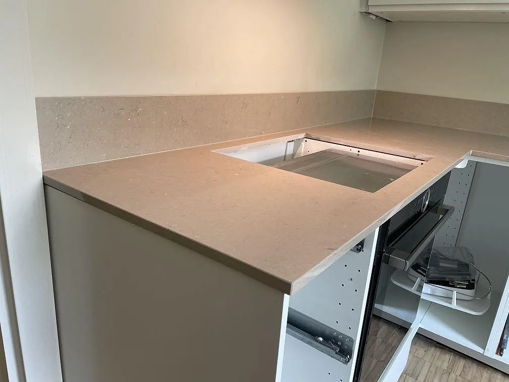 Polerad Silestone Coral Clay bänkskiva i Malmö med uppvikt stänkkant och utskärning för diskho i ett vitt kök.