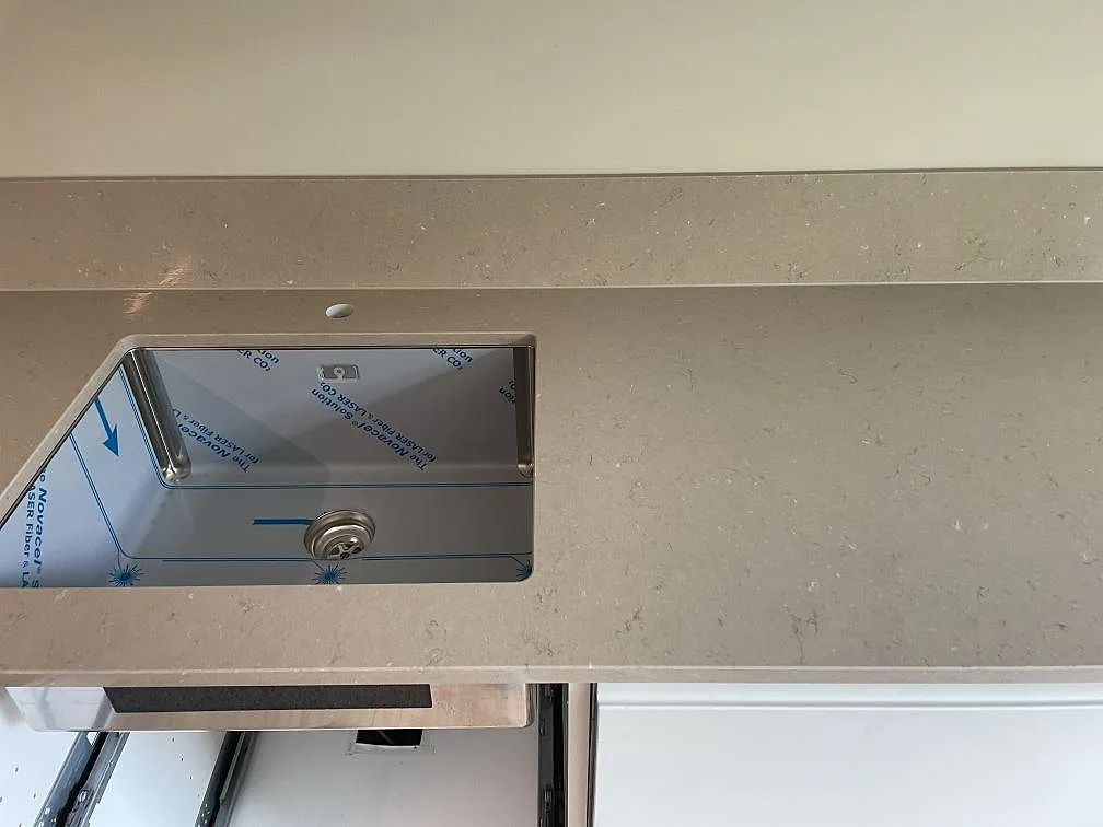 Köksbänkskiva i Silestone Coral Clay, polerad, med underlimmad rostfri diskho och stänkkant under montering i Malmö.