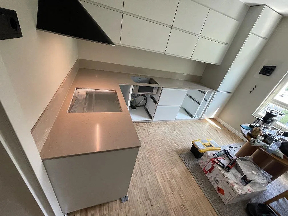 U-format kök i Malmö med halvö och polerad köksbänkskiva i Silestone Coral Clay, synlig diskho, hälluttag och stora fönster.