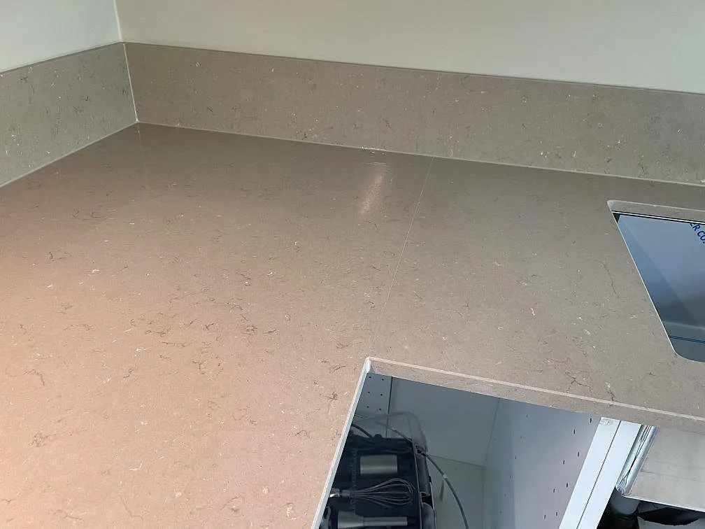 Hörn i polerad Silestone Coral Clay köksbänkskiva med matchande stänkkant och diskhoöppning i Malmö.