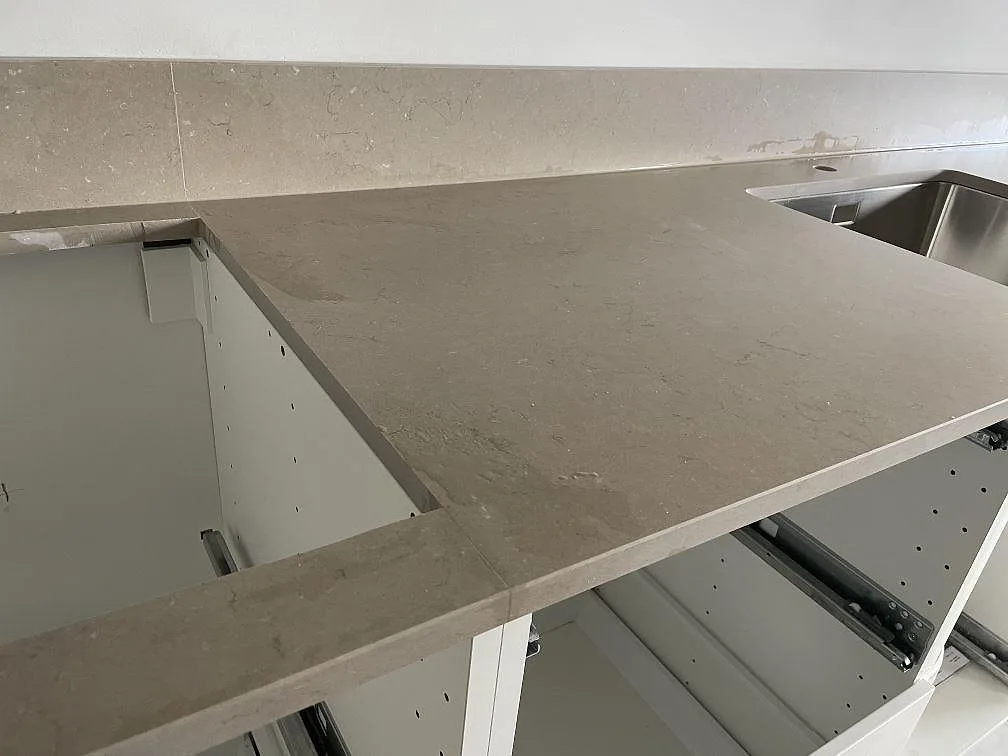 Närbild på Silestone Coral Clay köksbänkskiva i Mocka-yta med uppvikt stänkkant och rostfri diskho i ett vitt kök i Malmö.