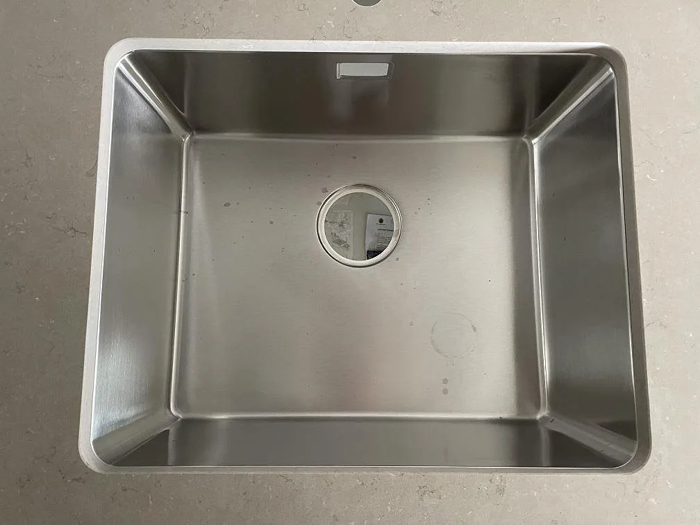 Underlimmad rostfri diskho i köksbänkskiva av Silestone Coral Clay komposit, fotograferad uppifrån under montering i Malmö.