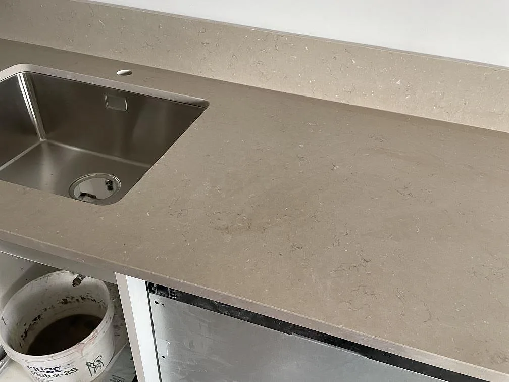 Detalj av Silestone Coral Clay bänkskiva med rostfri diskho, blandarhål och stänkkant i kök i Malmö.