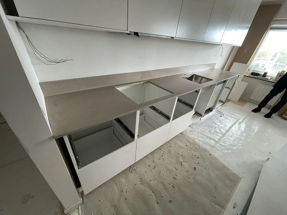 L-formad köksbänkskiva i Silestone Coral Clay komposit med Mocka-yta, stänkkant, hällurtag och rostfri diskho i ett kök i Malmö.