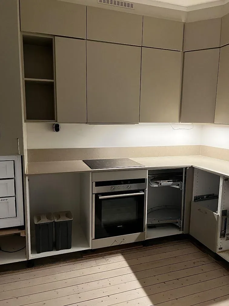 Polerad Silestone Coral Clay köksbänkskiva med häll, ljusa köksstommar och uppvikt stänkkant under montering i Malmö.