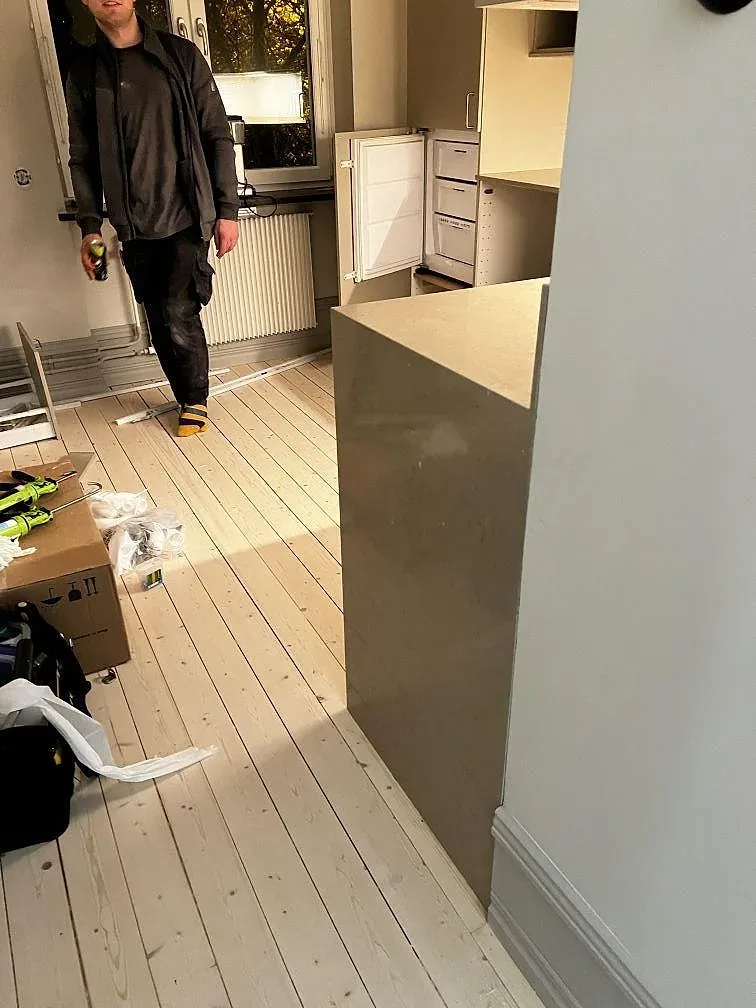 Monterad halvö i Silestone Coral Clay komposit med varm gråbeige stenkant under pågående köksmontering i Malmö.