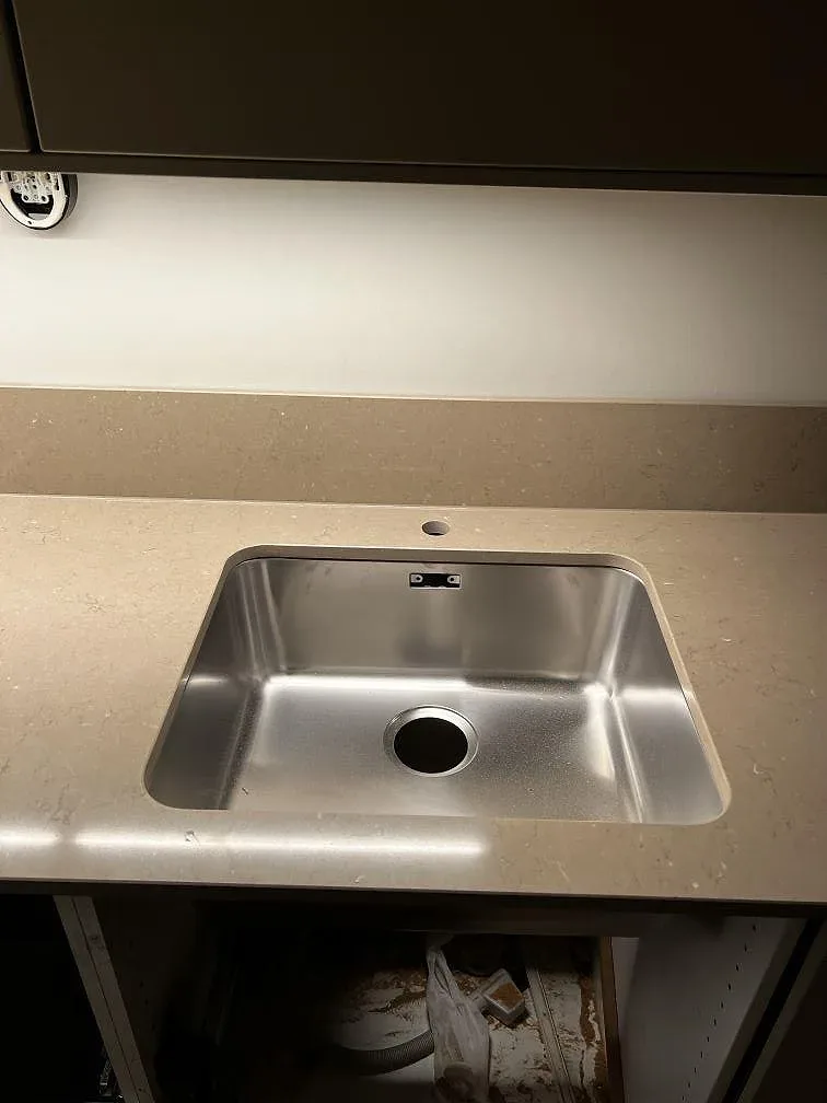Rostfri diskho ovanpå polerad Silestone Coral Clay bänkskiva, med 12 mm stänkkant och LED-belyst arbetsyta i Malmö.