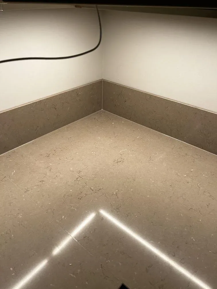 Hörnsektion av Silestone Coral Clay köksbänkskiva, polerad komposit, med matchande stänkkant och LED-reflektion i Malmö.