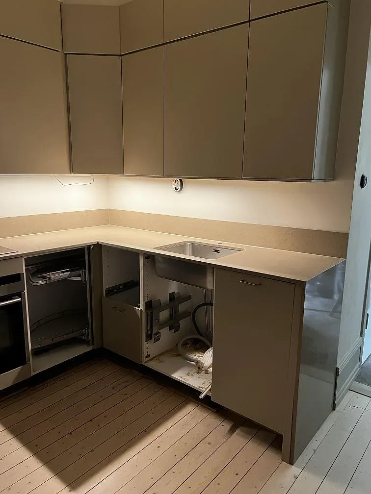 L-formad köksbänkskiva i polerad Silestone Coral Clay komposit, med uppvikt stänkkant och rostfri diskho i ett kök i Malmö.