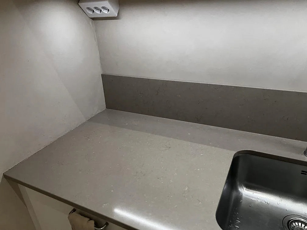 Närbild av polerad Silestone Coral Clay köksbänkskiva med matchande stänkskydd och rostfri diskho i Malmö.