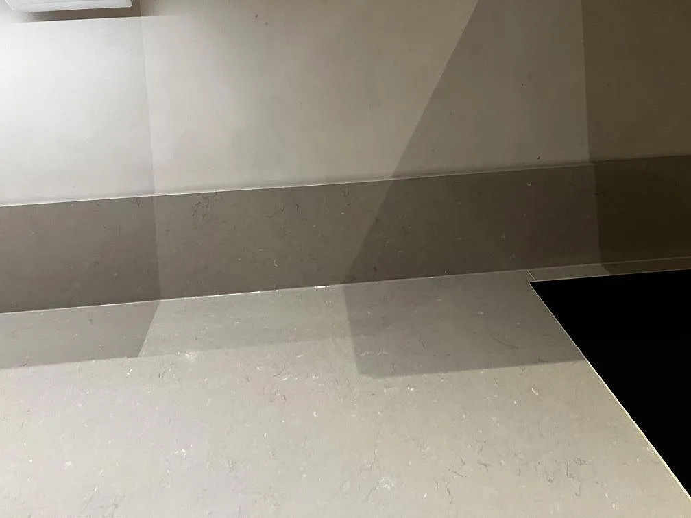 Polerad Silestone Coral Clay bänkskiva med infälld häll och uppvikt stänkskydd i ett kök i Malmö.