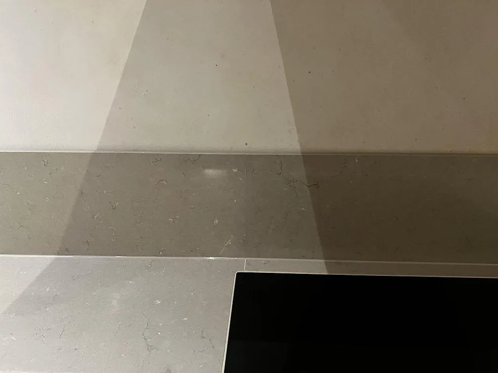 Närbild av greige Silestone Coral Clay med polerad yta, stänkskydd och hällkant under montering i Malmö.