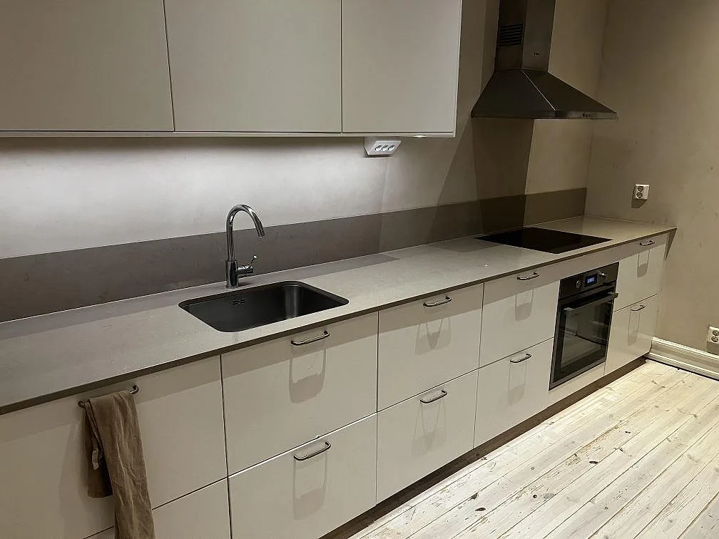 Köksbänkskiva i Silestone Coral Clay, polerad gråbeige komposit, med underlimmad rostfri diskho och infälld häll i ett kök i Malmö.