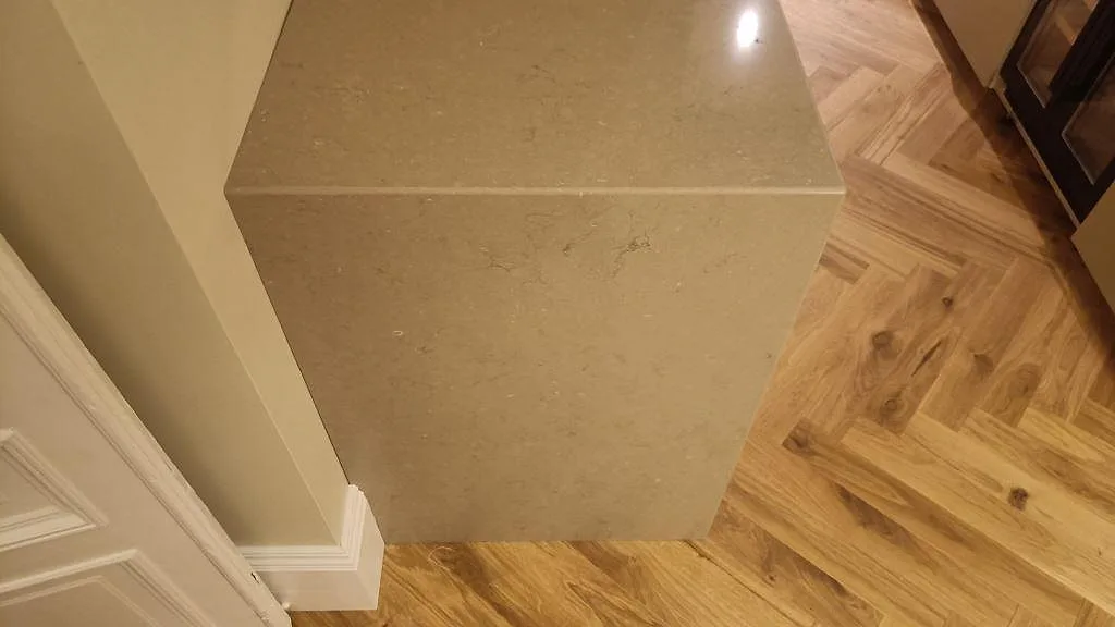 Gavel på köksö klädd med Silestone Coral Clay, polerad kvartskomposit, mot fiskbensgolv i Malmö.