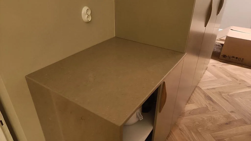 Sidobänk i polerad Silestone Coral Clay med låg stänkkant och vit köksstomme under montering i Malmö.