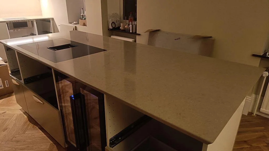 Köksö och bänkskiva i polerad Silestone Coral Clay, kvartskomposit, med svart induktionshäll i ett kök i Malmö.