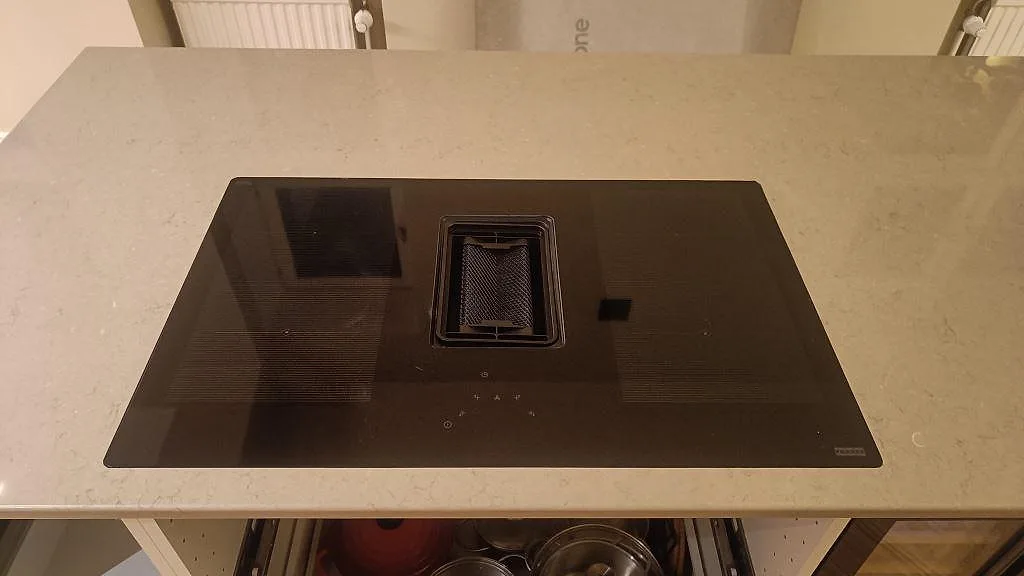 Svart induktionshäll monterad i polerad Silestone Coral Clay på köksö i ett kök i Malmö.