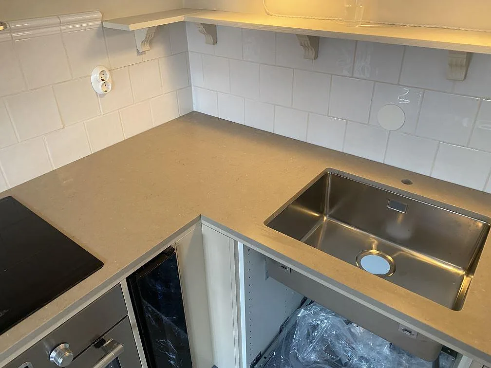 L-formad köksbänkskiva i Silestone Coral Clay komposit, 20 mm Mocka, med underlimmad rostfri diskho och induktionshäll i ett kök i Malmö.
