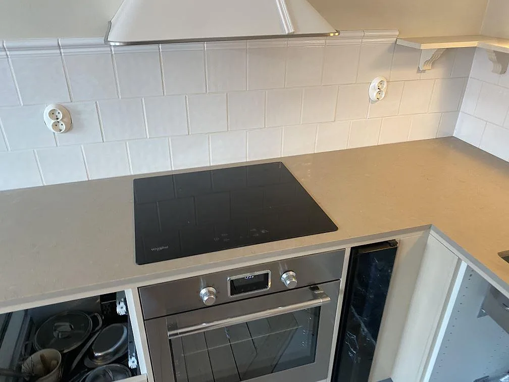 Hällsidan av en köksbänkskiva i Silestone Coral Clay komposit, matt Mocka-yta, med svart induktionshäll och ugn i Malmö.