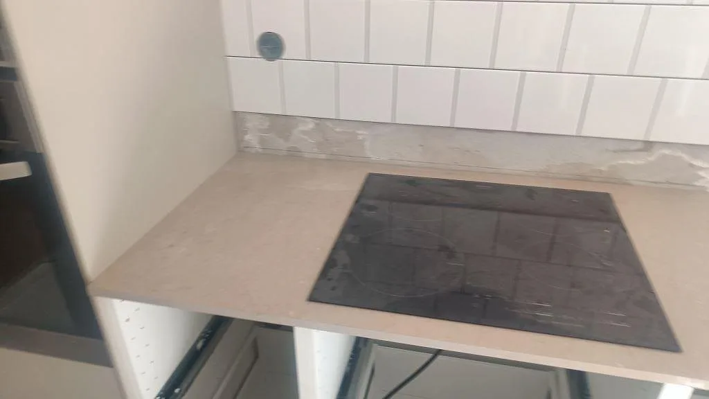 Sned närbild på svart häll i matt Silestone Coral Clay bänkskiva med delvis kaklad vägg i Malmö.
