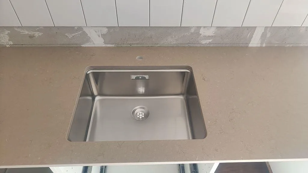 Närbild på underlimmad rostfri diskho i en matt Silestone Coral Clay bänkskiva i Malmö.