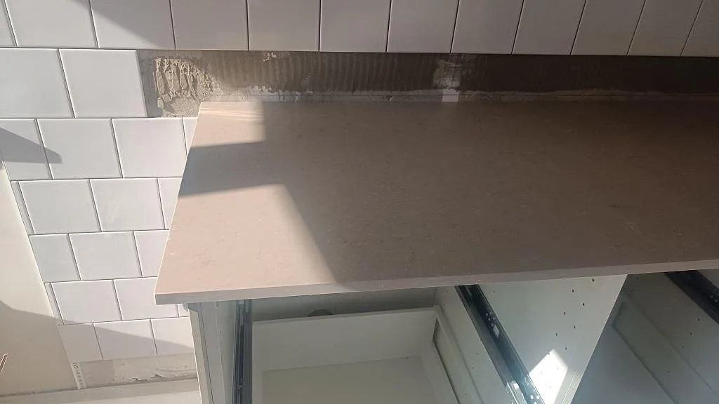 Detalj av matt Silestone Coral Clay bänkskiva över öppna köksstommar under montering i Malmö.