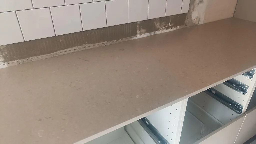 Lång arbetsyta i matt Silestone Coral Clay med varm gråbeige ton framför vit tunnelkakelvägg i Malmö.