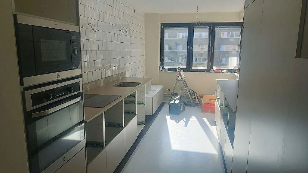 Köksbänkskiva i matt Silestone Coral Clay längs en vit tunnelkakelvägg under montering i Malmö.