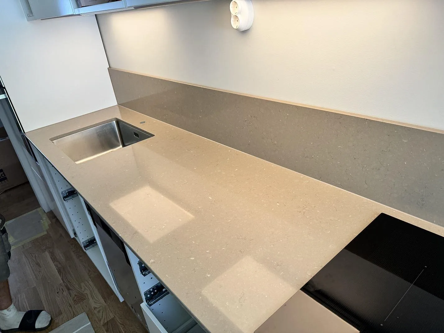 Köksbänkskiva i Silestone Coral Clay, polerad komposit, med rostfri diskho, svart häll och stänkskydd i ett kök i Malmö.
