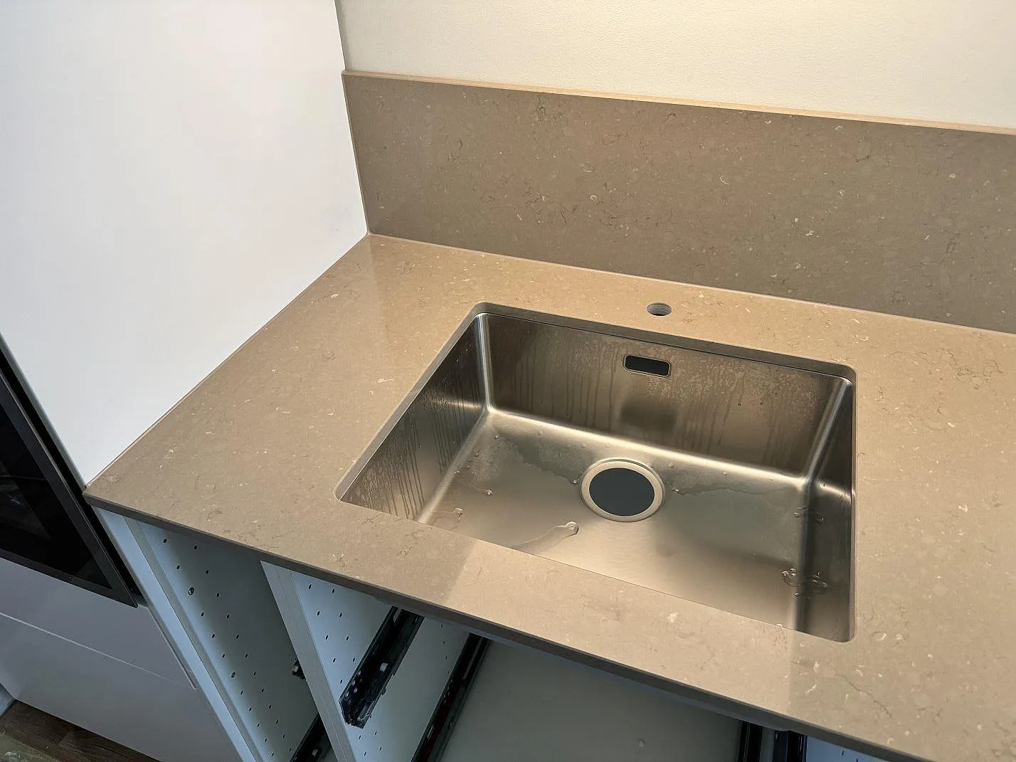 Diskhozonen med rostfri diskho i polerad Silestone Coral Clay och matchande stänkskydd i ett kök i Malmö.