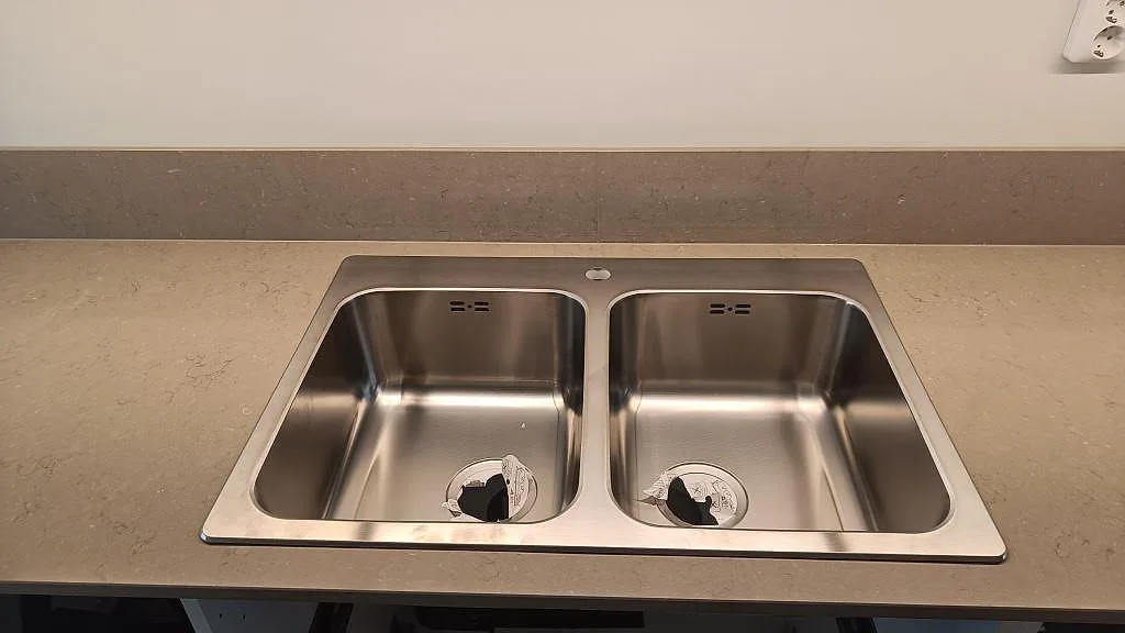 Ovanpåliggande dubbelho i rostfritt stål på polerad bänkskiva i Silestone Coral Clay med stänkkant i Malmö.