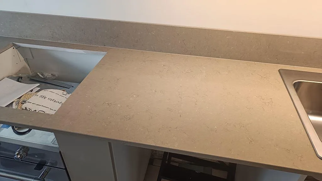 Polerad bänkskiva i Silestone Coral Clay med urtag för häll, rostfri diskho och uppvikt stänkkant i ett kök i Malmö.