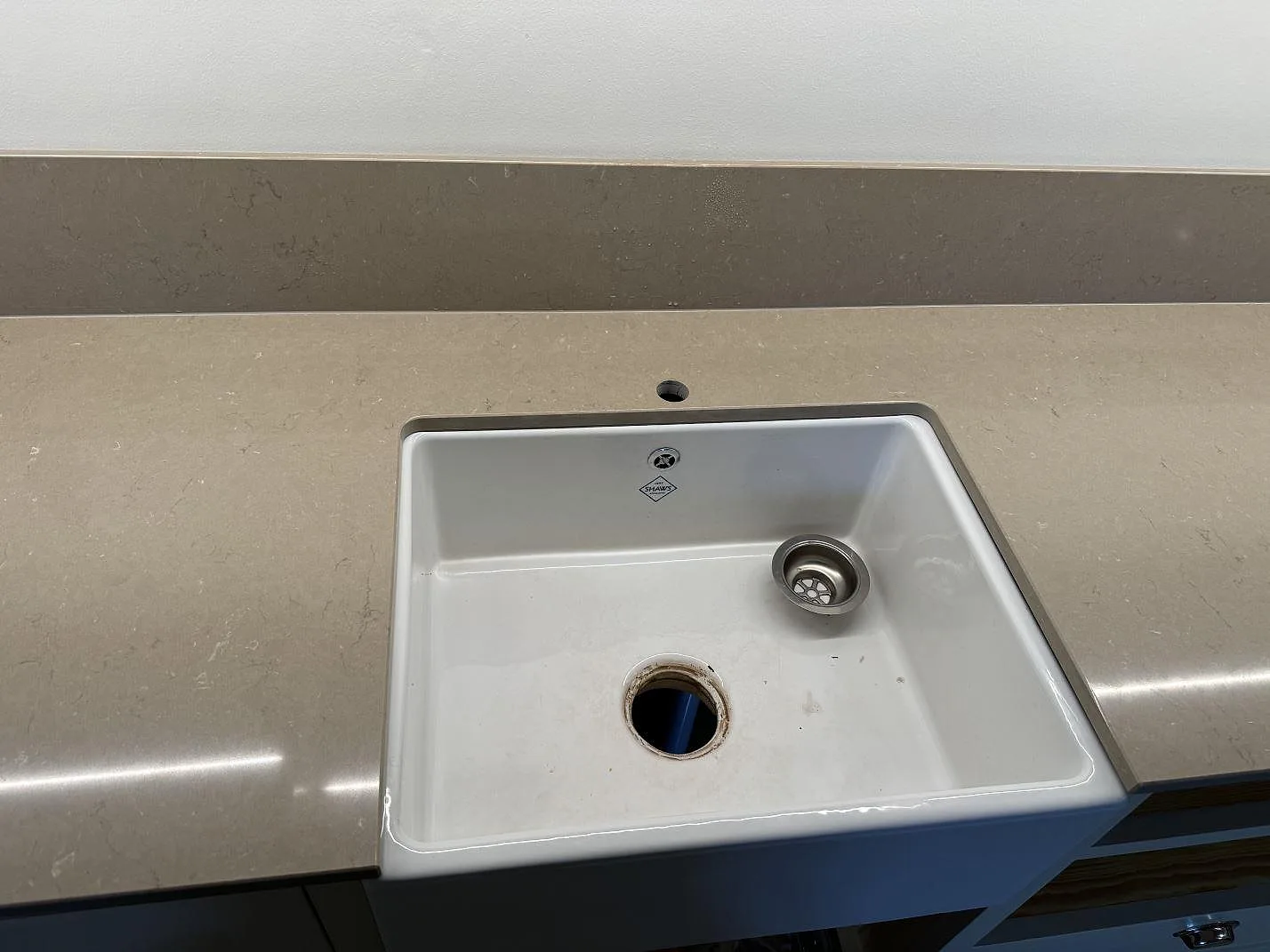 Närbild på polerad Silestone Coral Clay runt en vit diskho och ett lågt stänkskydd i Malmö.
