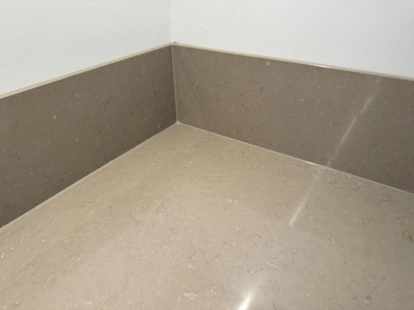 Detalj av polerad Silestone Coral Clay med matchande stänkskydd i ett hörn av köket i Malmö.