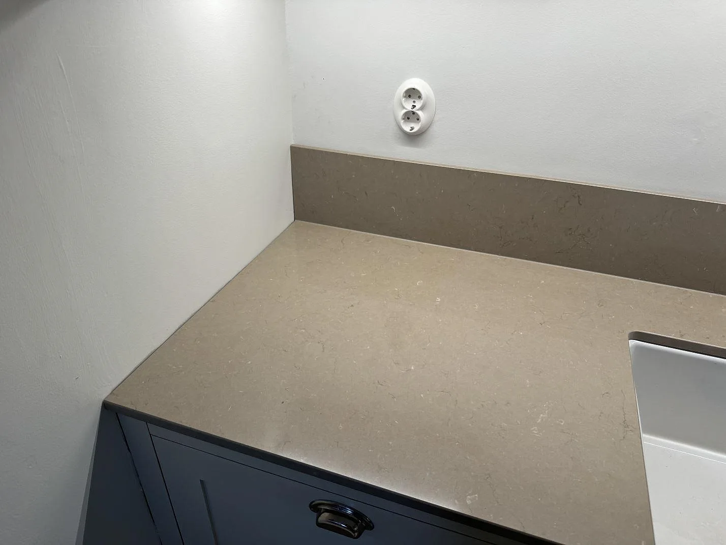 Polerad bänkskiva i Silestone Coral Clay med uppvikt stänkkant och vägguttag i ett Malmö-kök.