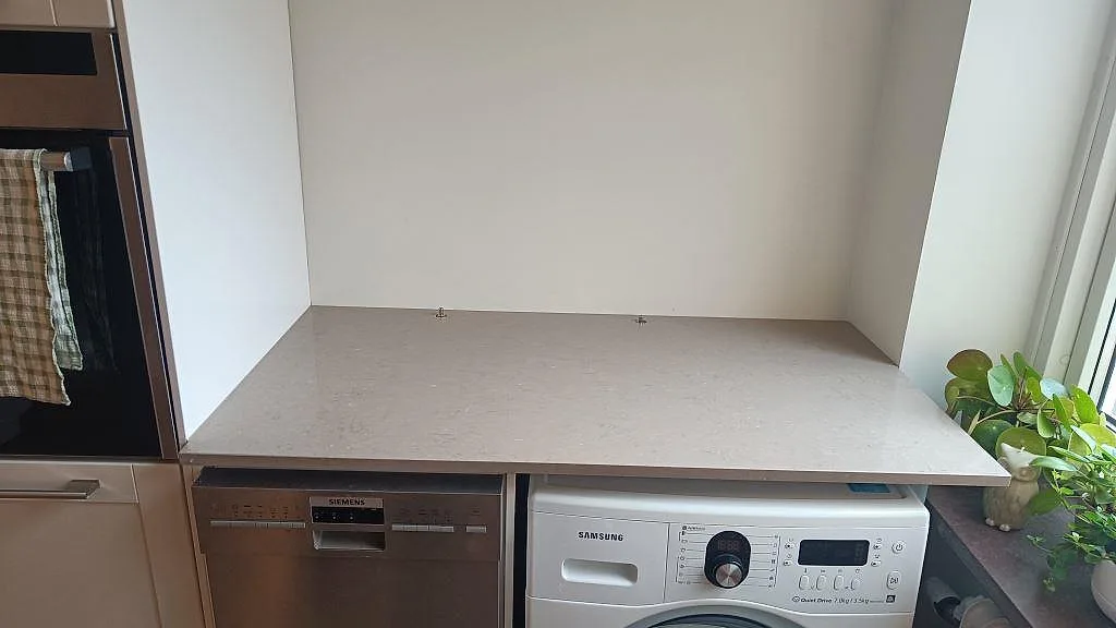 Arbetsyta i polerad Silestone Coral Clay, gråbeige kvartskomposit, monterad över vitvaror i Malmö.