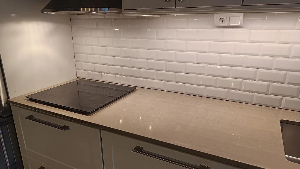 Lång köksbänkskiva i polerad Silestone Coral Clay, gråbeige kvartskomposit, med häll och rostfri diskho i Malmö.