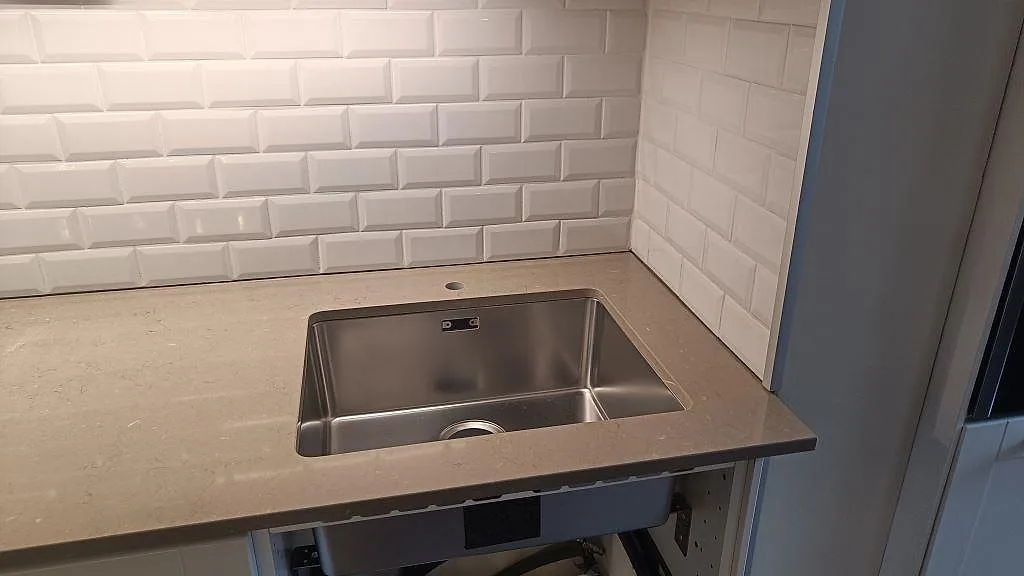 Rostfri diskho monterad under polerad Silestone Coral Clay, gråbeige kvartskomposit, i ett kök i Malmö.