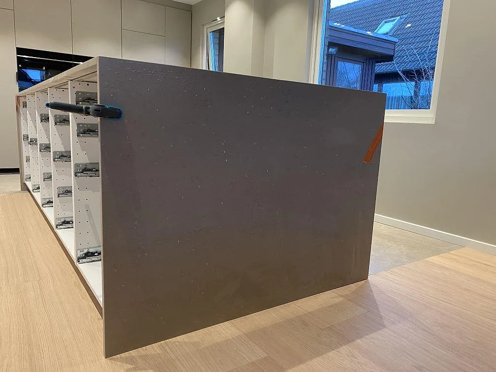 Stenklädd gavelsida på köksö i polerad Silestone Coral Clay, med varm taupe yta och öppna köksstommar i Malmö.