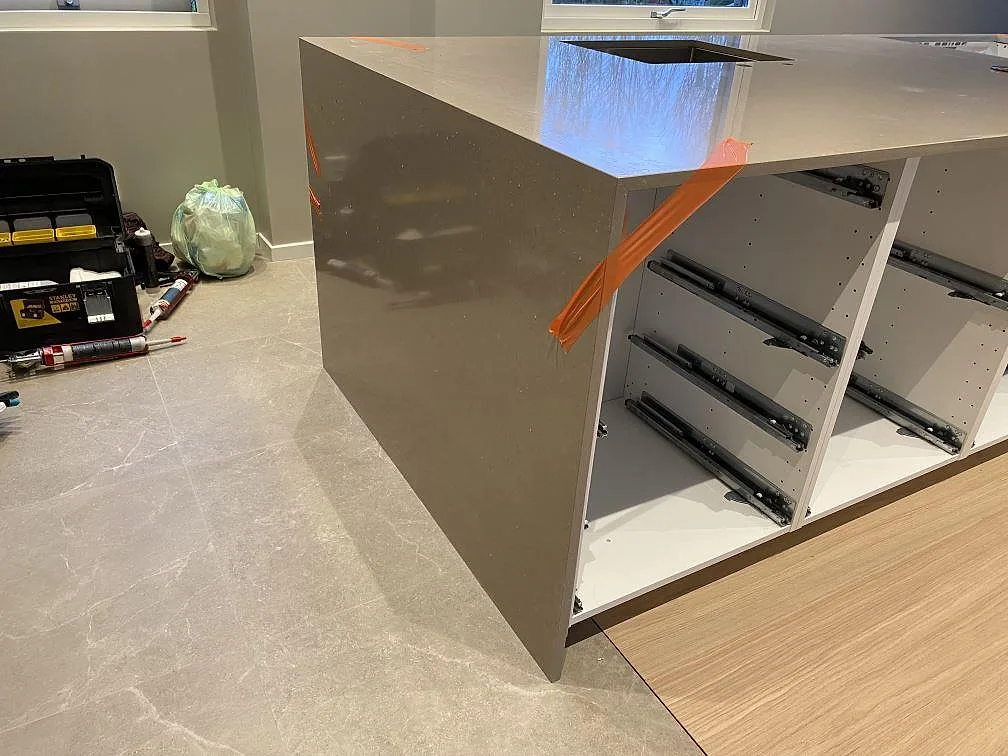 Detalj av waterfall-gavel och hällurtag i polerad Silestone Coral Clay på en köksö under montering i Malmö.