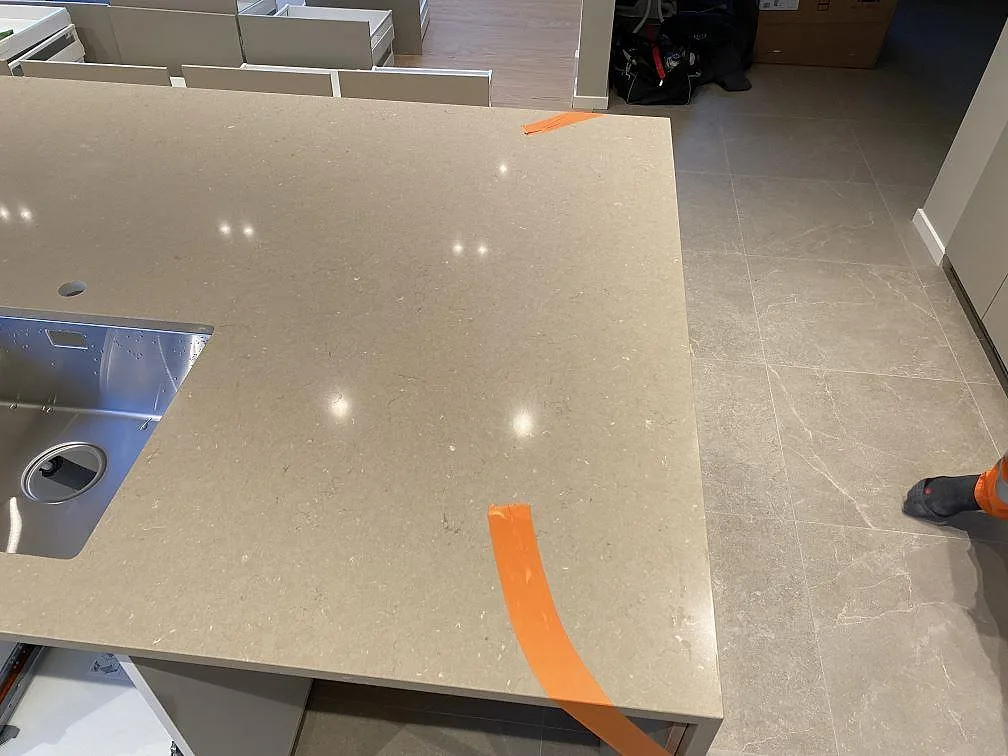 Närbild på polerad Silestone Coral Clay runt en rostfri diskho på köksön i Malmö.