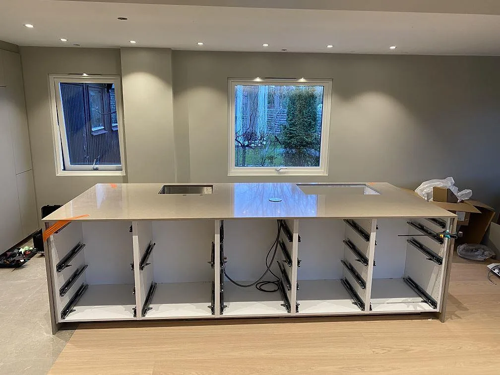 Frontvy av köksbänkskiva i polerad Silestone Coral Clay på öppna köksstommar, med rostfri diskho och hällurtag i Malmö.
