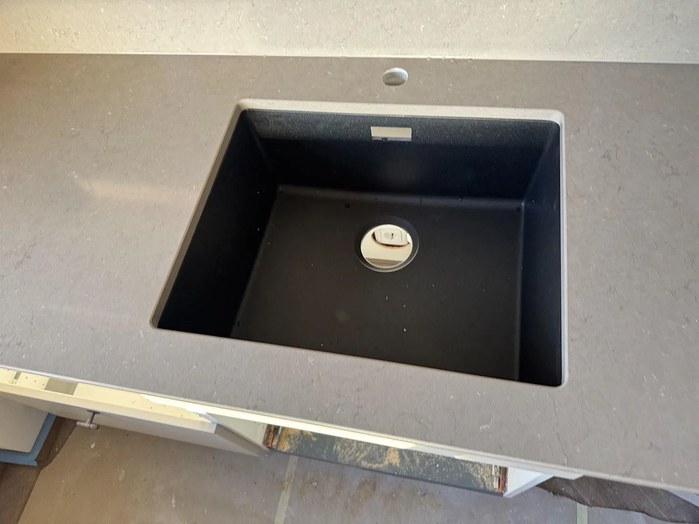 Detalj av svart underlimmad diskho i polerad Silestone Coral Clay, grå kvartskomposit, i ett kök i Malmö.