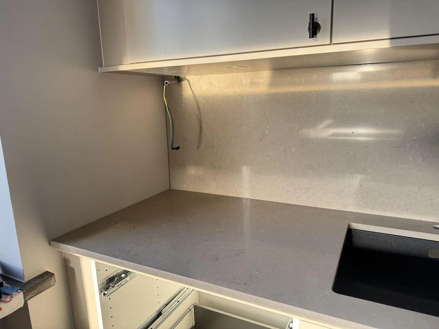 Väggmonterad köksbänkskiva i polerad Silestone Coral Clay, kvartskomposit, med svart underlimmad diskho och stänkskydd i Malmö.