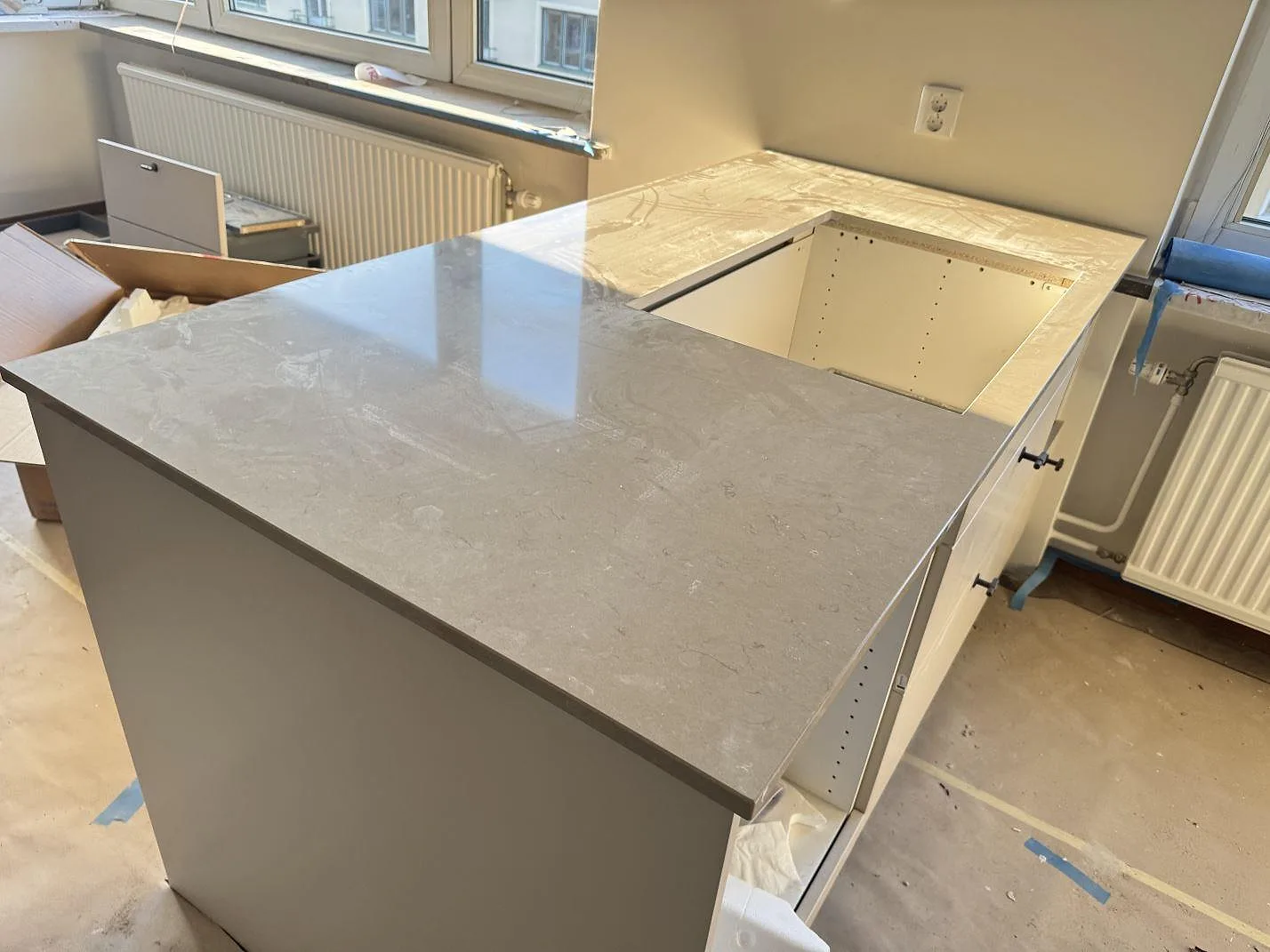 Polerad köksö i Silestone Coral Clay, grå kvartskomposit, med stor urtagning och öppna stommar under montering i Malmö.
