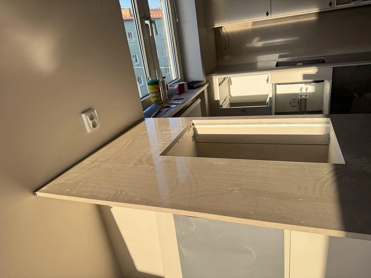 Närbild av polerad Silestone Coral Clay i kvartskomposit på köksö med stor urtagning och väggmonterad arbetsyta i Malmö.