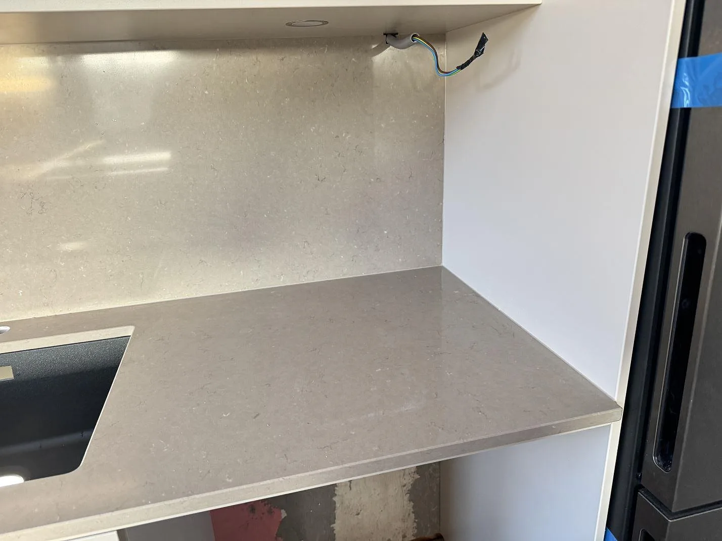 Polerad Silestone Coral Clay i kvartskomposit som bänkskiva och stänkskydd med svart underlimmad diskho i Malmö.