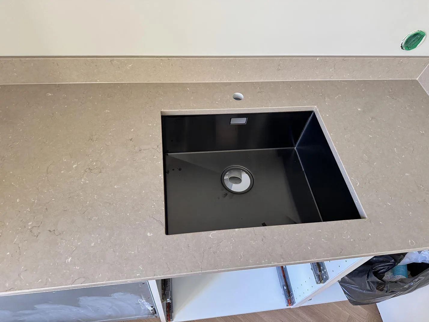 Köksbänkskiva i Silestone Coral Clay, polerad kvartskomposit, med svart diskho och låg stänkkant i ett kök i Malmö.